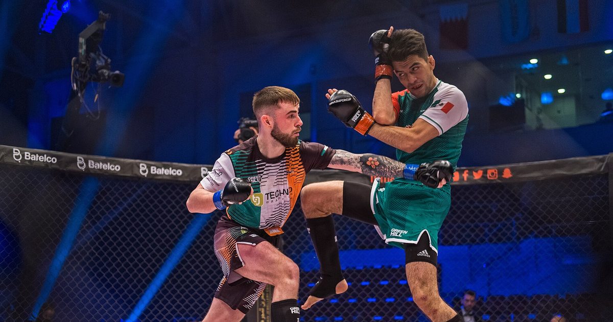 An amateur fighter throws a high kick as his opponent covers up in the cage at the 2022 IMMAF World Championships in Bahrain